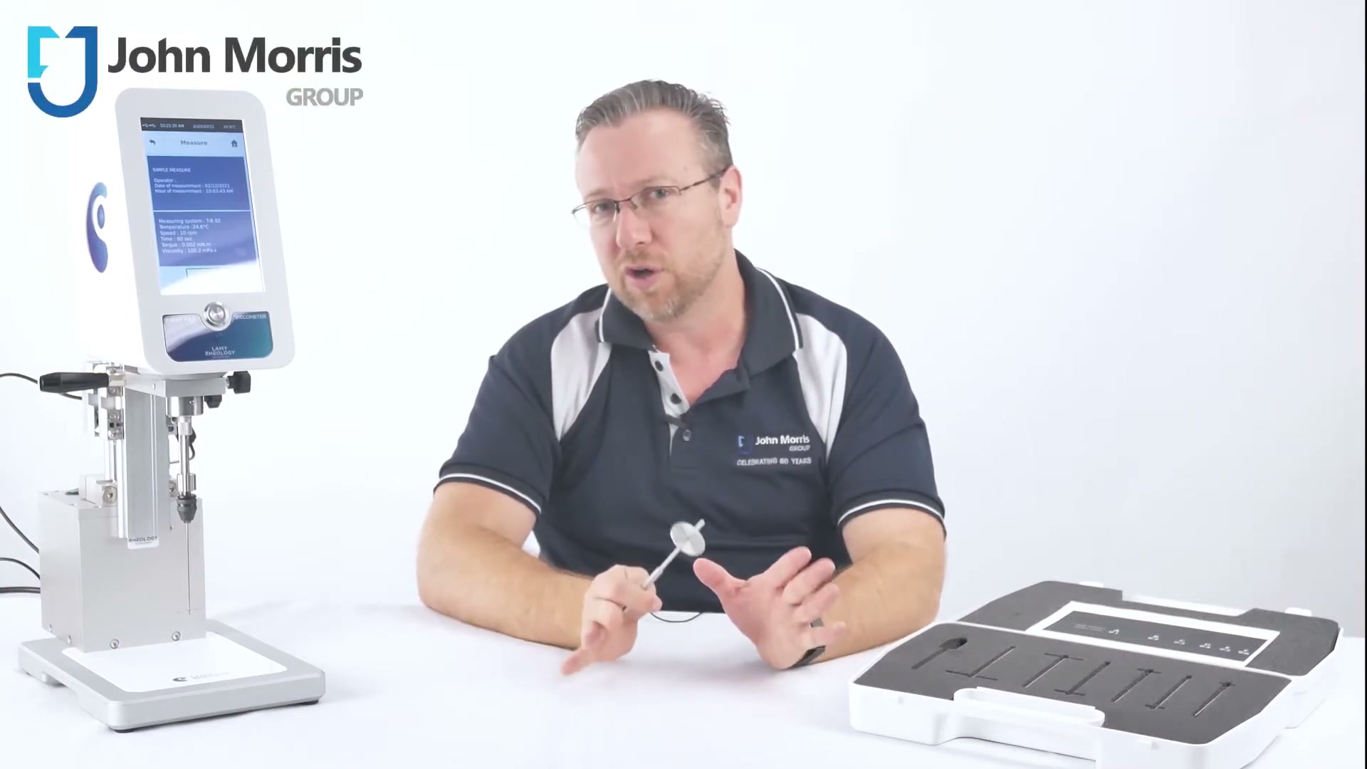 John Morris Group specialist holding a T-bar spindle next to a Lamy viscometer and the HELIPRO carry case