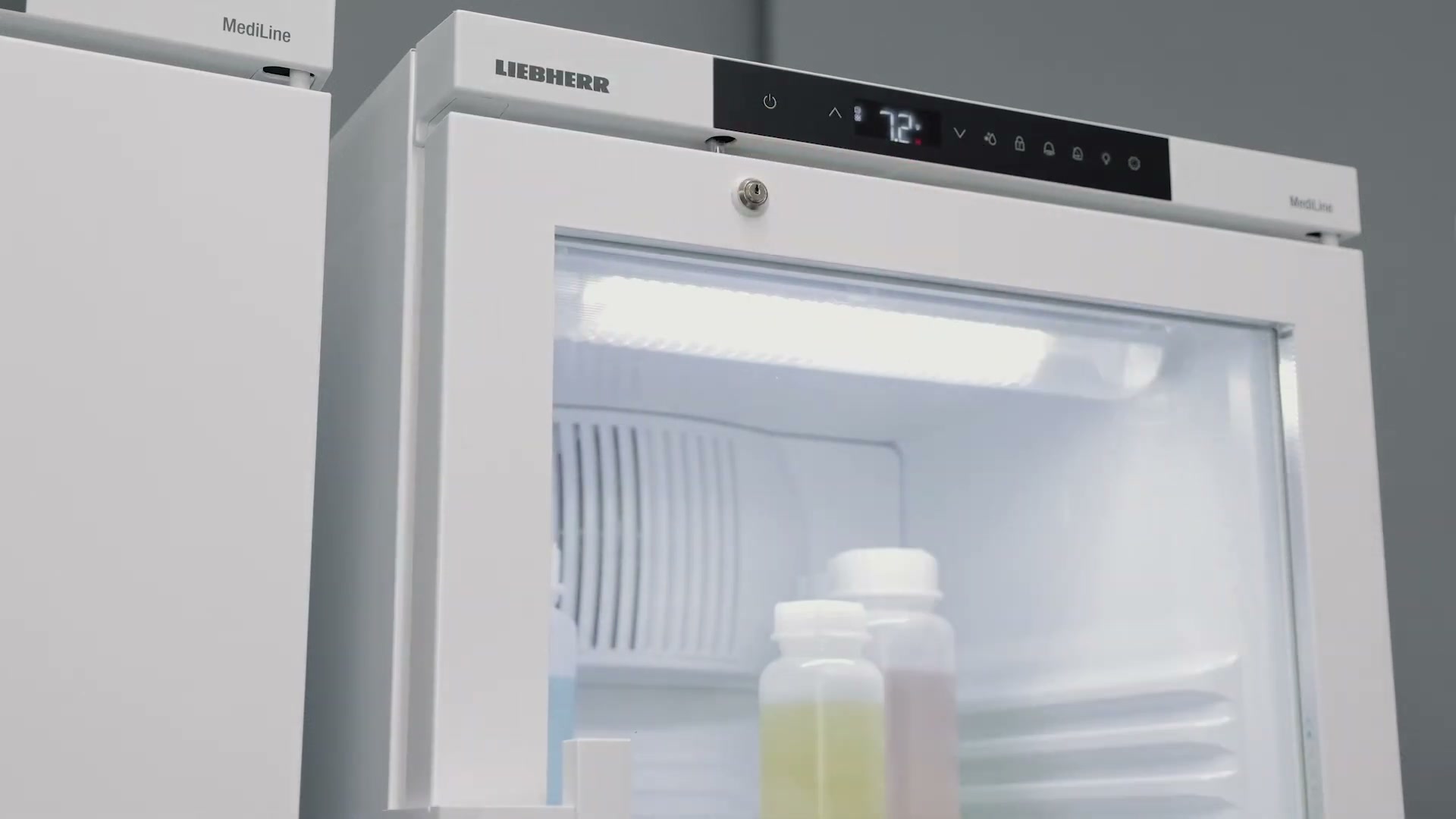 Lab technician opening a Liebherr unit with plastic interior shelving and stored sample boxes